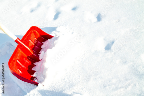 Close up of big red plastic showel in the process of removing the snow in winter