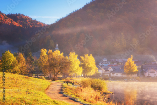 Beautiful foggy and frosty autumn morning landscape with lake, small village and mountains, outdoor travel background, Dedinky, National park Slovak paradise (Narodny park Slovensky Raj), Slovakia