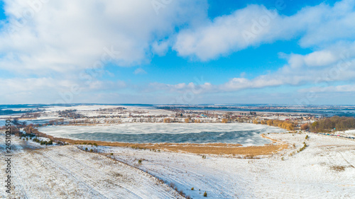 Aerial Drone Photograph of a Partly Frozen Lake Surrounded with Beautiful Winter Colors of the Fields and Forest