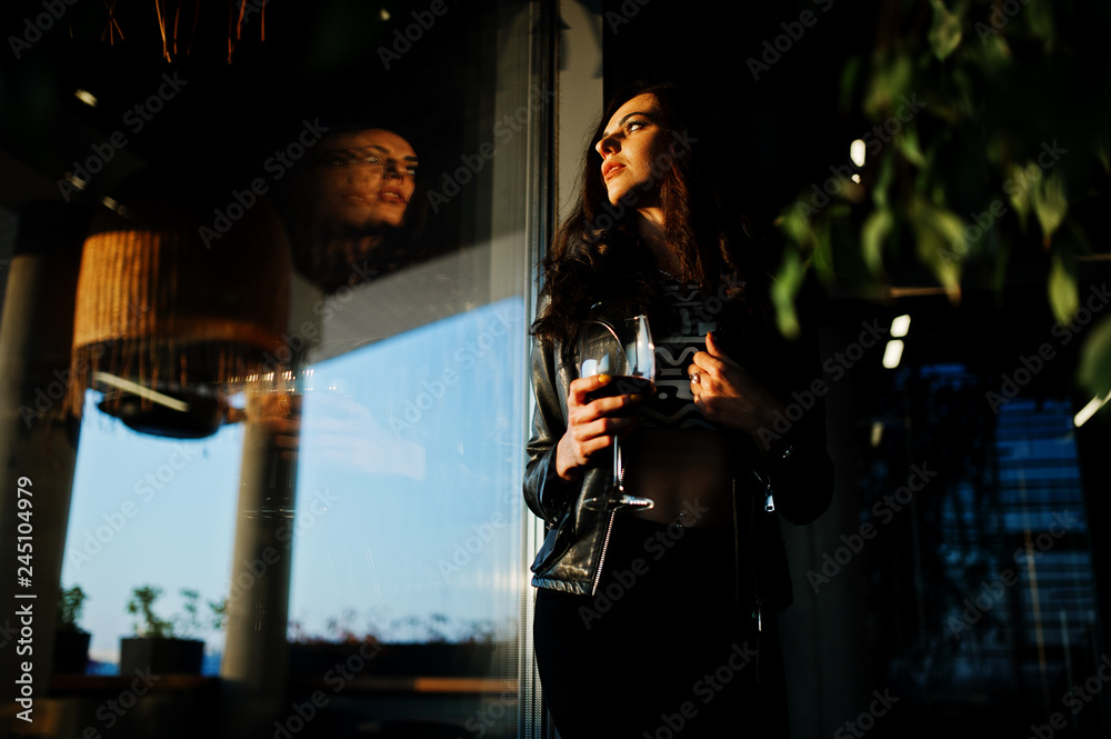 Young curly woman enjoying  her wine in a bar.