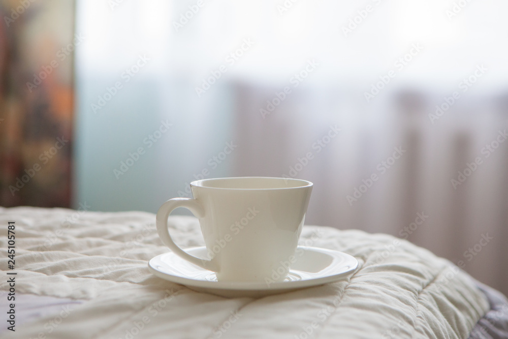Morning cup of coffee on the background of the bed and the window Morning cup of coffee on the background of the bed and the window