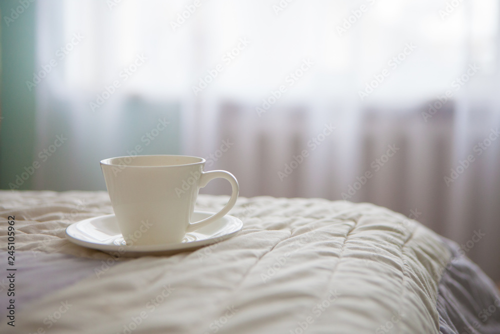 Morning cup of coffee on the background of the bed and the window Morning cup of coffee on the background of the bed and the window