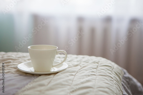 Morning cup of coffee on the background of the bed and the window