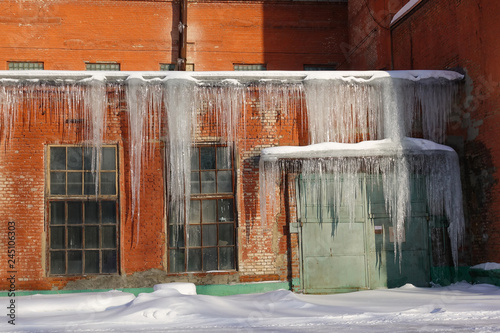The old factory of the Soviet period of red brick in the winter. Big icicles on the roof. Winter. The Moscow Region. Russia