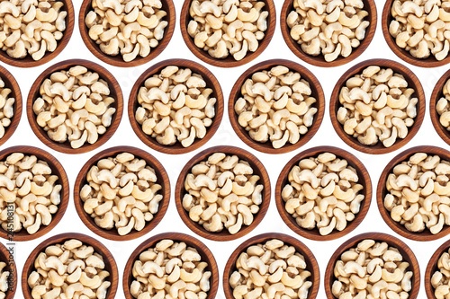 Cashew nuts in a wooden cedar plate on a white isolated background. Row of bowls with cashew nuts, top view. Cashew nuts pattern