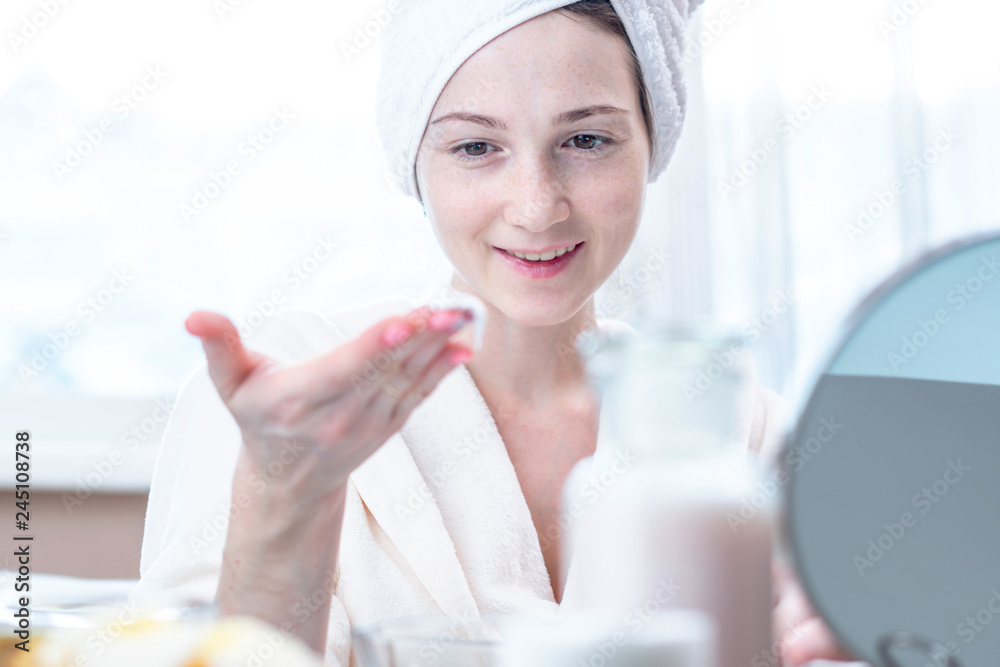 Beautiful woman applying cream of natural cosmetics on face moisturizing the skin. Hygiene and care for the skin at home Beautiful woman applying cream of natural cosmetics on face moisturizing the skin. Hygiene and care for the skin at home