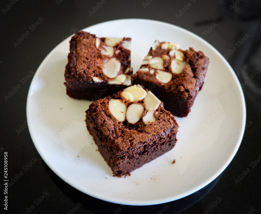 brownies cake on the table / piece of chocolate cake cocoa with nut on top view brownies slice on white plate brownies cake on the table / piece of chocolate cake cocoa with nut on top view brownies slice on white plate