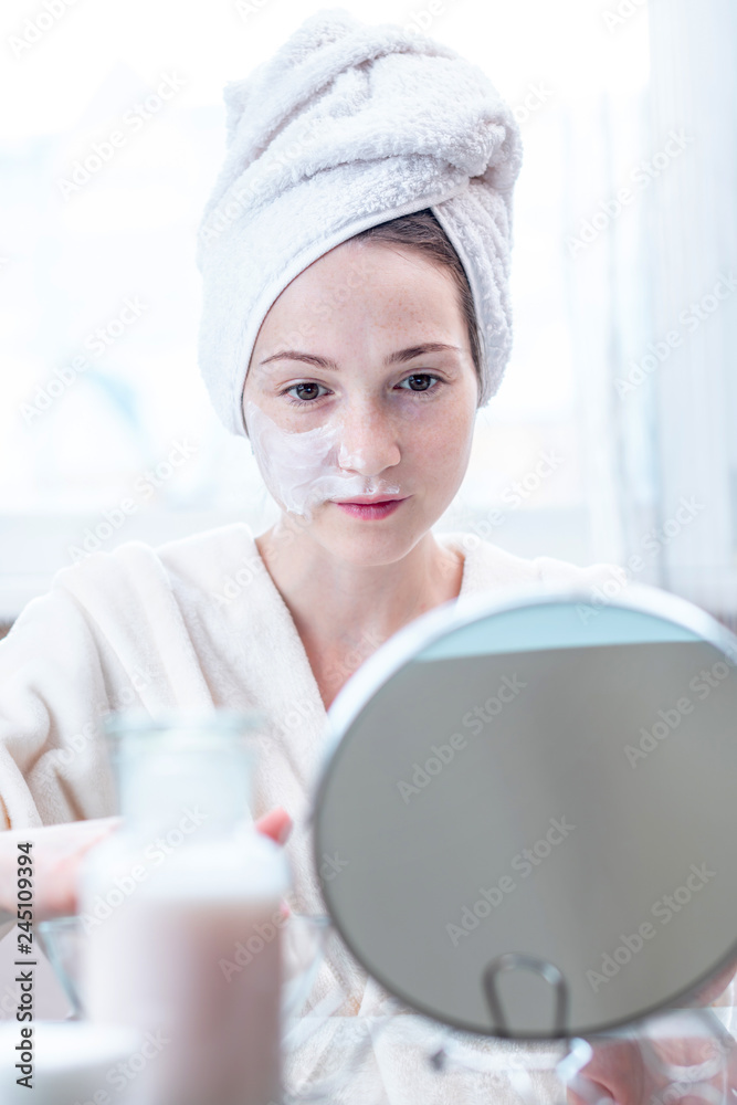 Beautiful happy young woman applying cream on face moisturizing the skin. Concept of hygiene and care for the skin Beautiful happy young woman applying cream on face moisturizing the skin. Concept of hygiene and care for the skin