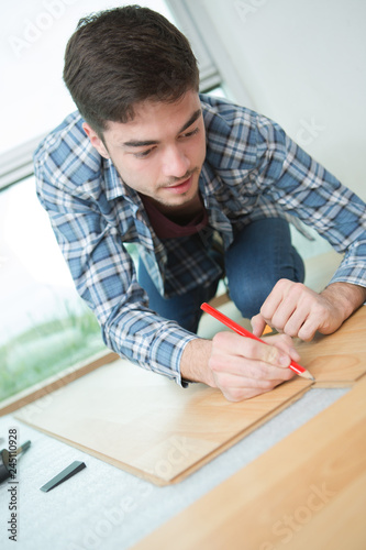 man measuring new wooden laminate flooring