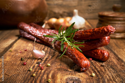 Smoked sausage on a wooden rustic table with the addition of fresh aromatic herbs and spices, natural product, produced by traditional methods