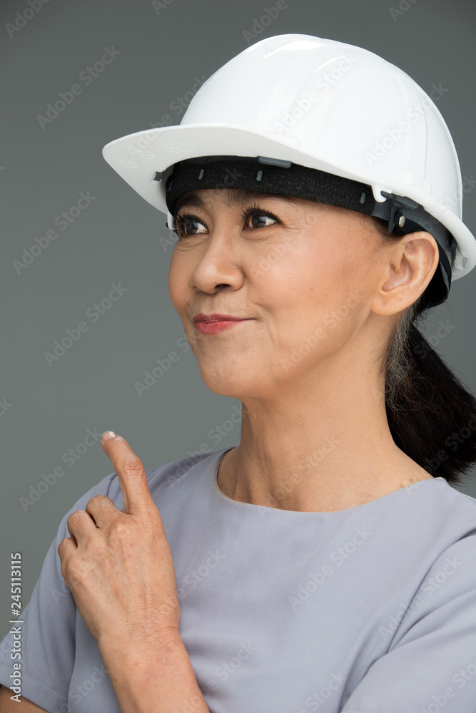 Beautiful Asian Smart Architect Engineer 50s 60s years old woman in white hard hat helmet look at camera, portrait studio lighting gray background copy space, concept aging society woman can do Beautiful Asian Smart Architect Engineer 50s 60s years old woman in white hard hat helmet look at camera, portrait studio lighting gray background copy space, concept aging society woman can do
