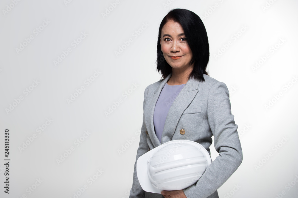 Beautiful Asian Smart Architect Engineer 50s 60s years old woman in white hard hat helmet look at camera, portrait studio lighting gray background copy space, concept aging society woman can do Beautiful Asian Smart Architect Engineer 50s 60s years old woman in white hard hat helmet look at camera, portrait studio lighting gray background copy space, concept aging society woman can do
