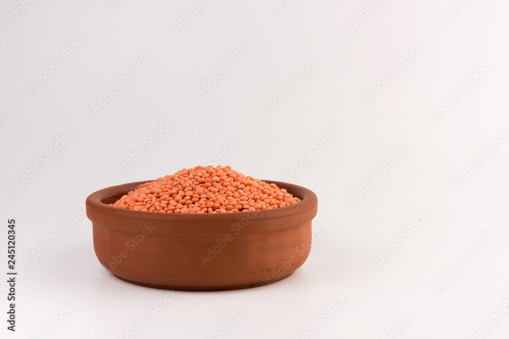 Red lentils in clay plate isolated on white background Red lentils in clay plate isolated on white background