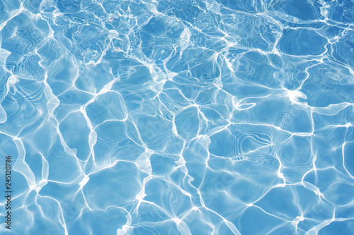 Fotografia Blue water surface with bright sun light reflections, water in swimming pool bac