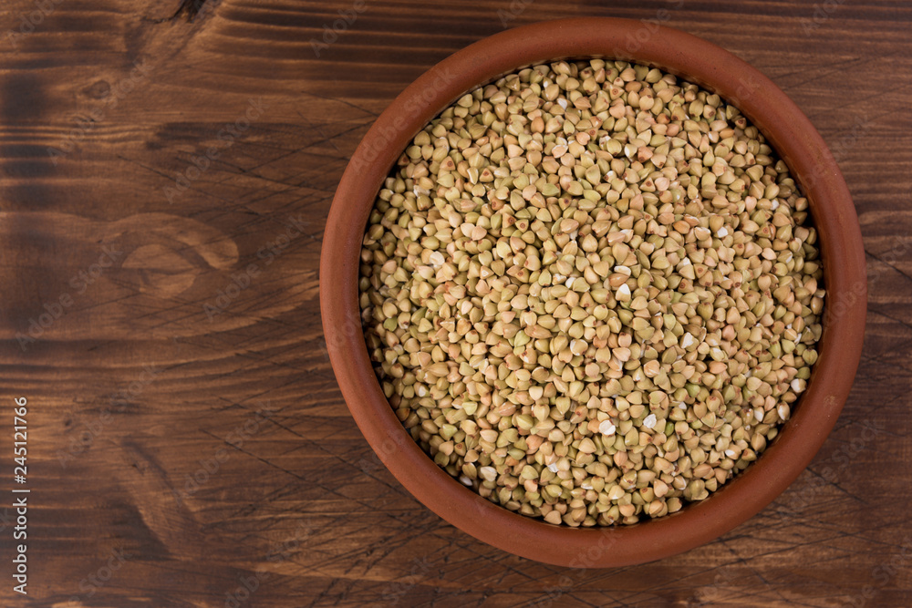 Natural fresh green buckwheat in clay bowl on wooden background. Top view Natural fresh green buckwheat in clay bowl on wooden background. Top view