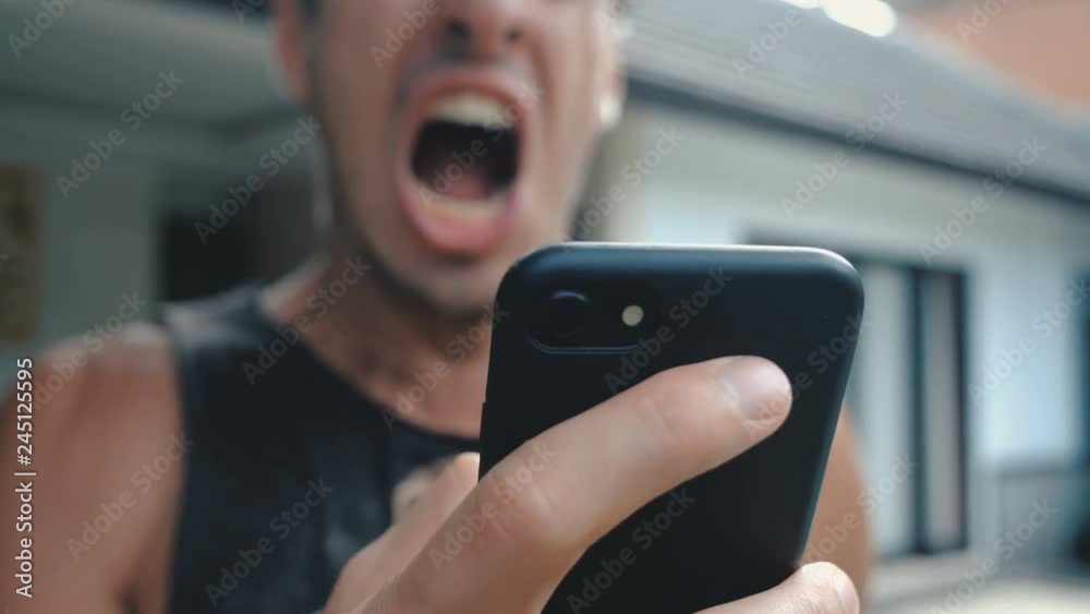 Angry Man Using Smartphone. Furious yelling man with smartphone in hand