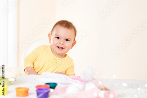 Baby girl sitting at the table and painting holiday easter eggs smiling happy childhood concept