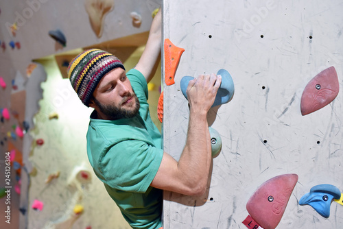 climber bouldering in a sports hall - holding on to the handle of an artificial rock wall