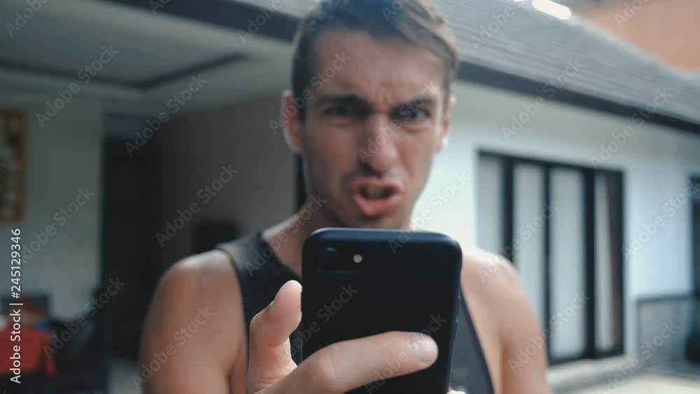 Angry Man Using Smartphone. Man is angry with the message that he read in the smartphone. Angry man uses smartphone.