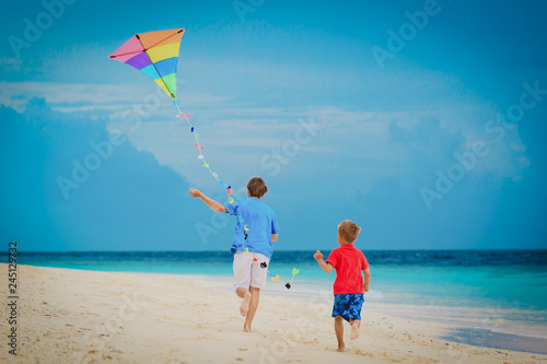 father and little son flying kite on beach