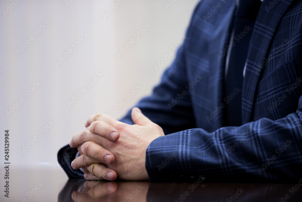 A man in a dark suit gesticulates with his hands during a speech