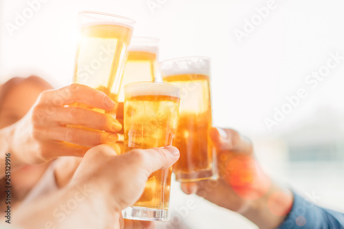 Group of happy friends drinking beer outdoors together - concept of friendship and celebration