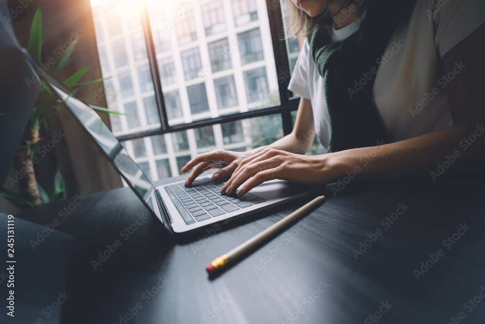 Woman working on laptop keyboard at the office wile sitting at the table