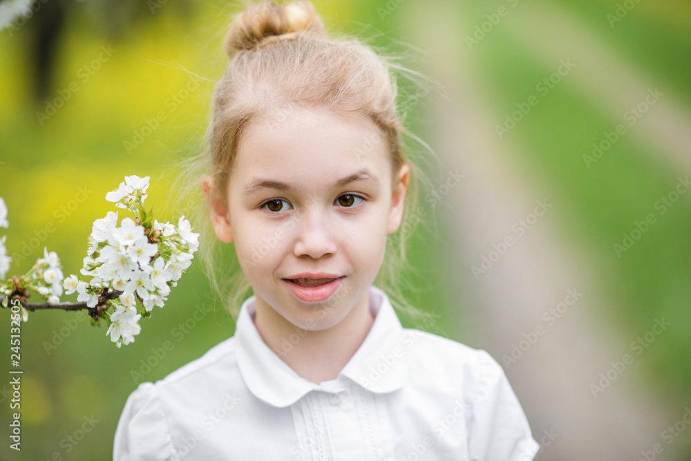 Portrait of a blonde girl near the branch of white blossom cherry in the flowering garden Portrait of a blonde girl near the branch of white blossom cherry in the flowering garden