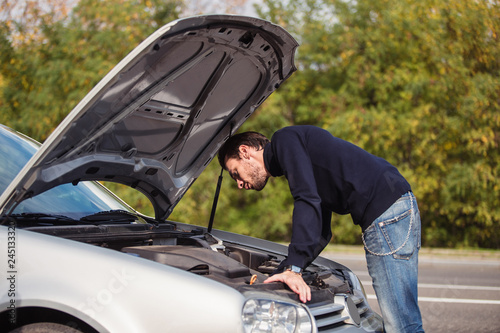 A man tries to repair the car on the road
