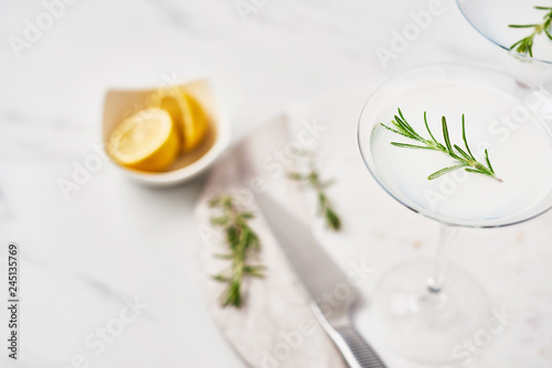 Summer drink. Refreshing summer alcoholic cocktail Margarita with rosemary and citrus fruits or sparkling gin and lemonade on white marble table. Copy space. Selective focus.