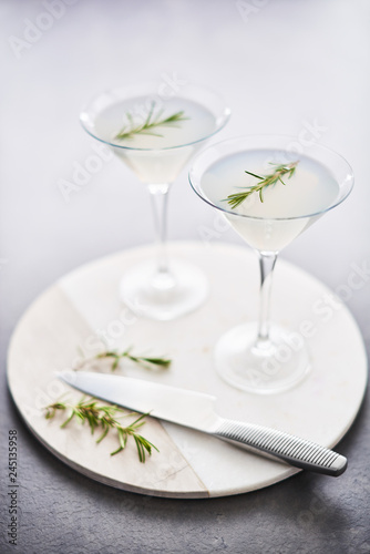 Summer drink. Refreshing summer alcoholic cocktail with rosemary or sparkling gin and lemonade on marble serving plate over dark concrete table. Copy space for text. Selective focus.