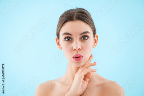 Happy cheerful beautiful young woman posing isolated over blue background.