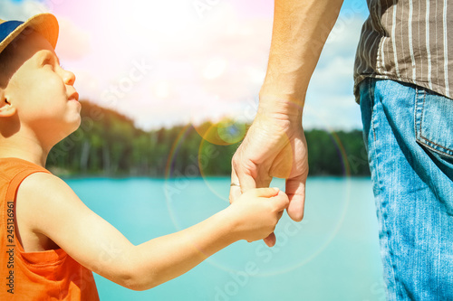 hands of a parent and child in nature in a park by the sea