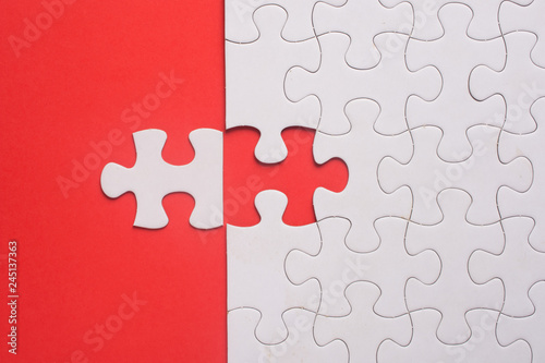 Incomplete white jigsaw puzzle pieces on red background