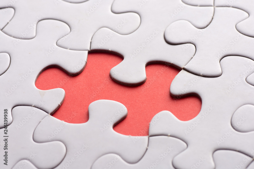 Unfinished white jigsaw puzzle pieces on red background Unfinished white jigsaw puzzle pieces on red background