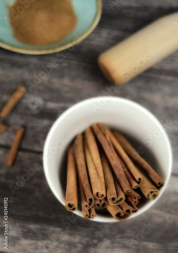Ground cinnamon, cinnamon sticks and powder on old wooden background in rustic style