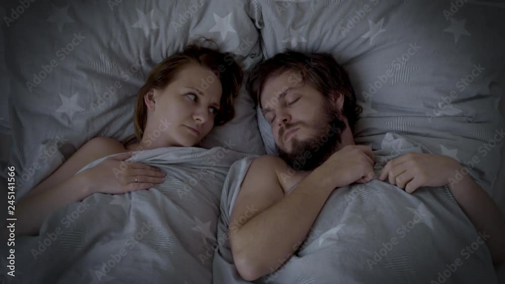 Man Snoring in Bed, Woman cannot sleep. Husband snoring, his Wife is