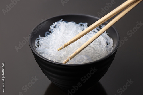 Rise noodles in black bowl on wooden background