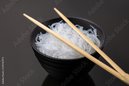 Rise noodles in black bowl on wooden background