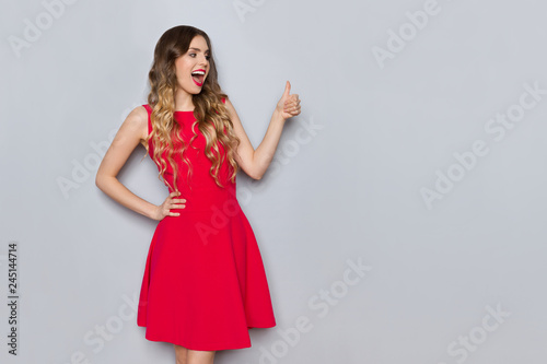 Excited Beautiful Woman In Red Dress Is Showing Thumb Up
