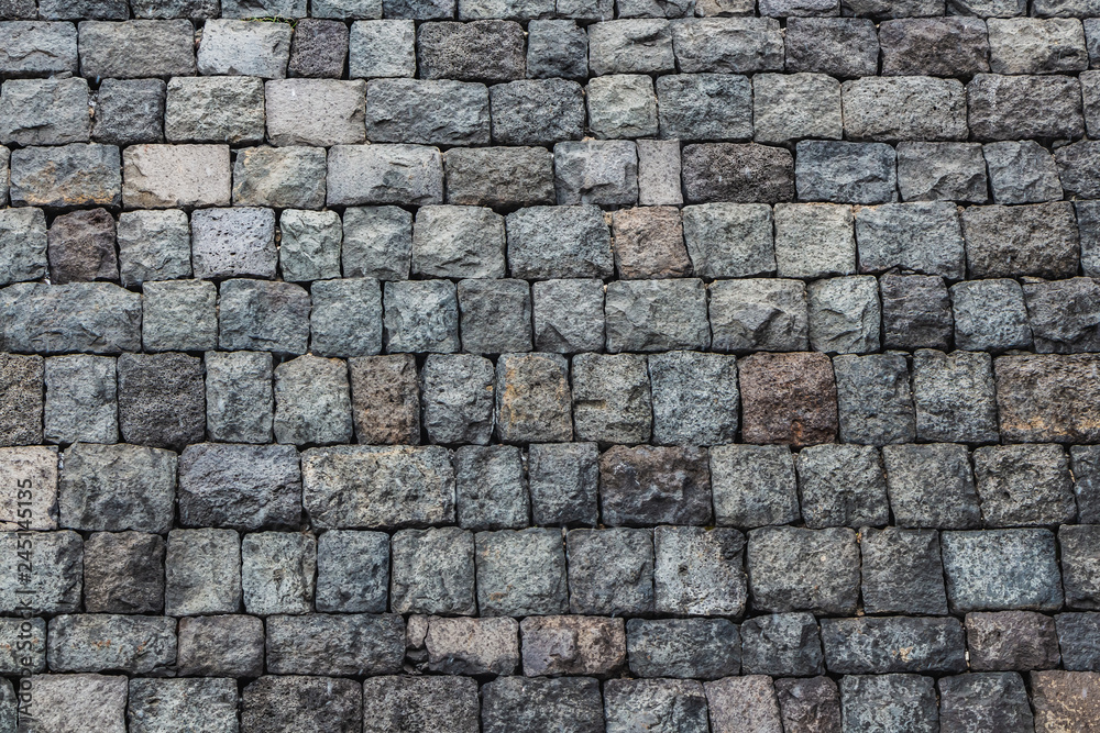 A beautiful horizontal texture of part of an old gray brick wall from frozen volcanic lava from Etna volcano in Sicily in Italy on the photo A beautiful horizontal texture of part of an old gray brick wall from frozen volcanic lava from Etna volcano in Sicily in Italy on the photo
