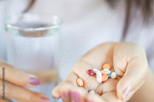 closeup woman hand taking vitamins another hand holding glass of water 