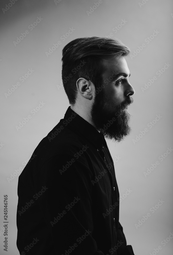 Black and white photo portrait of a man with a beard in profile dressed in the black shirt on the white background Black and white photo portrait of a man with a beard in profile dressed in the black shirt on the white background