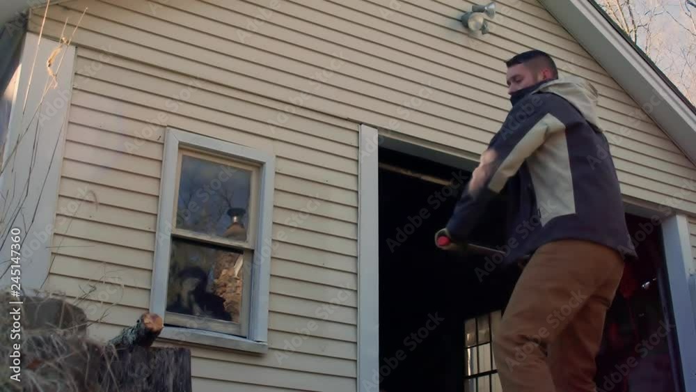 Wood goes flying past camera from strong axe swing & strike from young man Wood goes flying past camera from strong axe swing & strike from young man