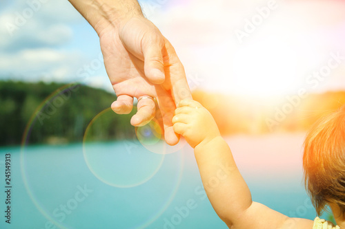 hands of a parent and child in nature in a park by the sea
