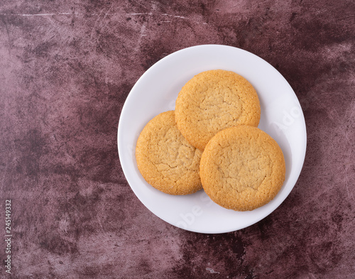 Top view of three soft sugar cookies on a white plate atop a red background