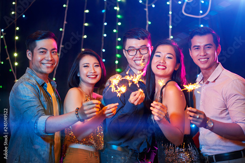 Cheerful Vietnamese young people with burning sparklers in hands