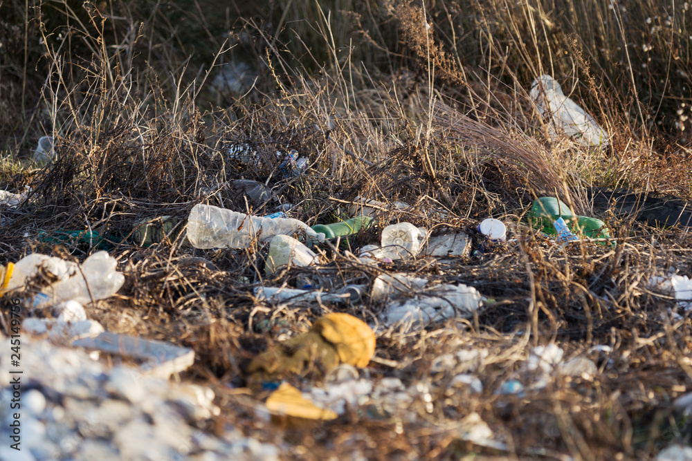 Spilled garbage on the beach of a big city. Empty used dirty plastic bottles. Dirty sea, sandy coast of the Black Sea. Environmental pollution. Ecological problem Spilled garbage on the beach of a big city. Empty used dirty plastic bottles. Dirty sea, sandy coast of the Black Sea. Environmental pollution. Ecological problem