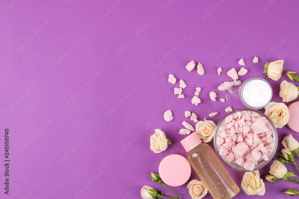 cosmetics for face and body in pink bottles with fresh roses on a bright purple background. cream and lotion, sea salt and soap. spa. view from above. space for text cosmetics for face and body in pink bottles with fresh roses on a bright purple background. cream and lotion, sea salt and soap. spa. view from above. space for text