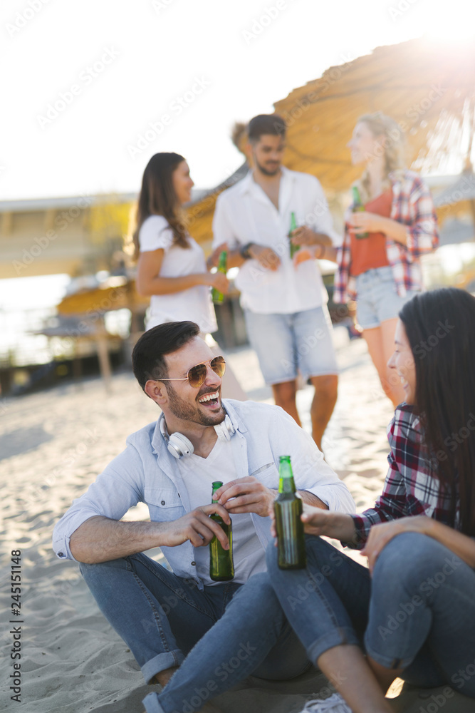 Obraz premium Happy couple smiling and drinking beer at beach